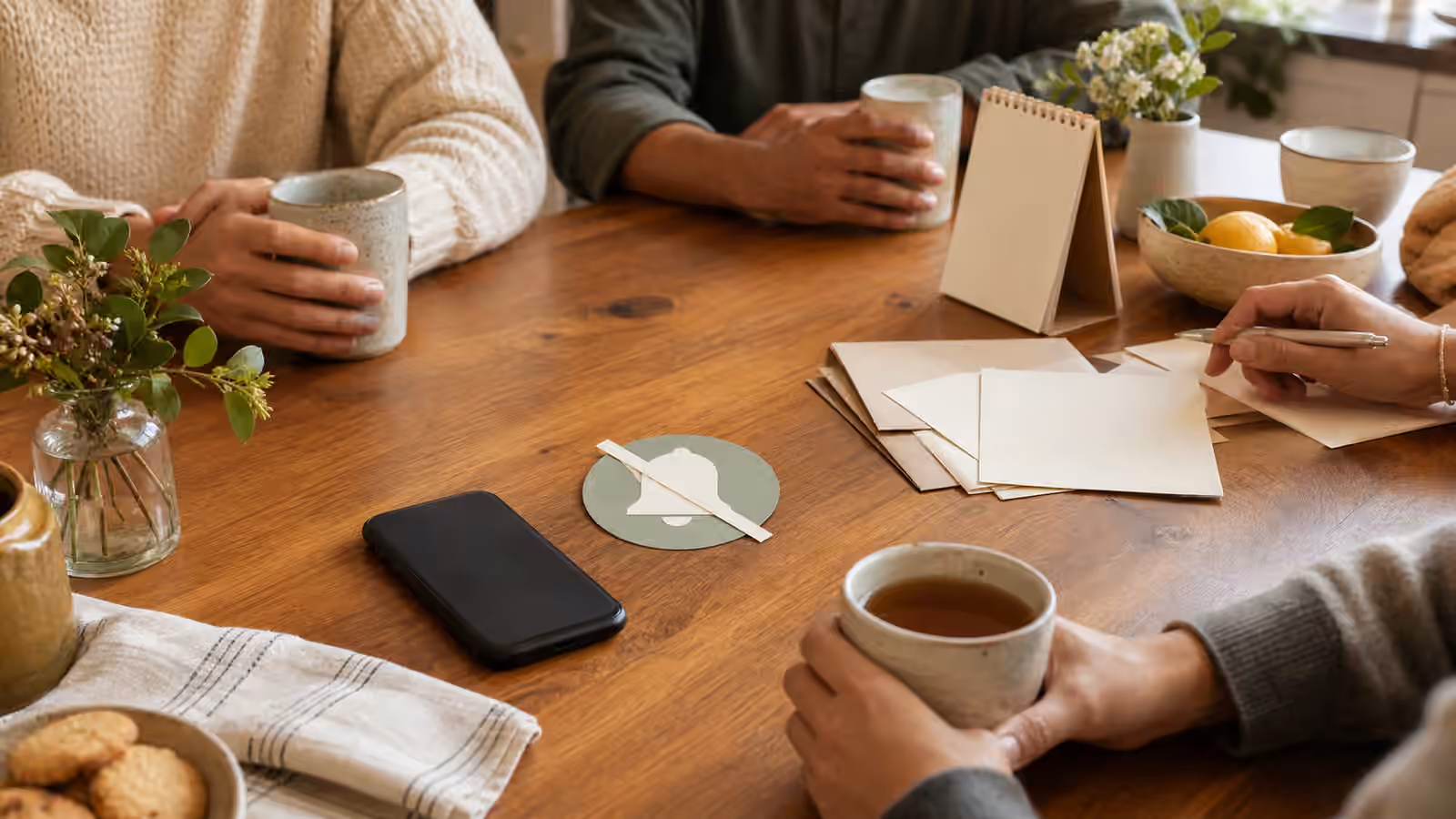 a small table with tea, blank invitation cards, a face-down phone, and a quiet notification icon
