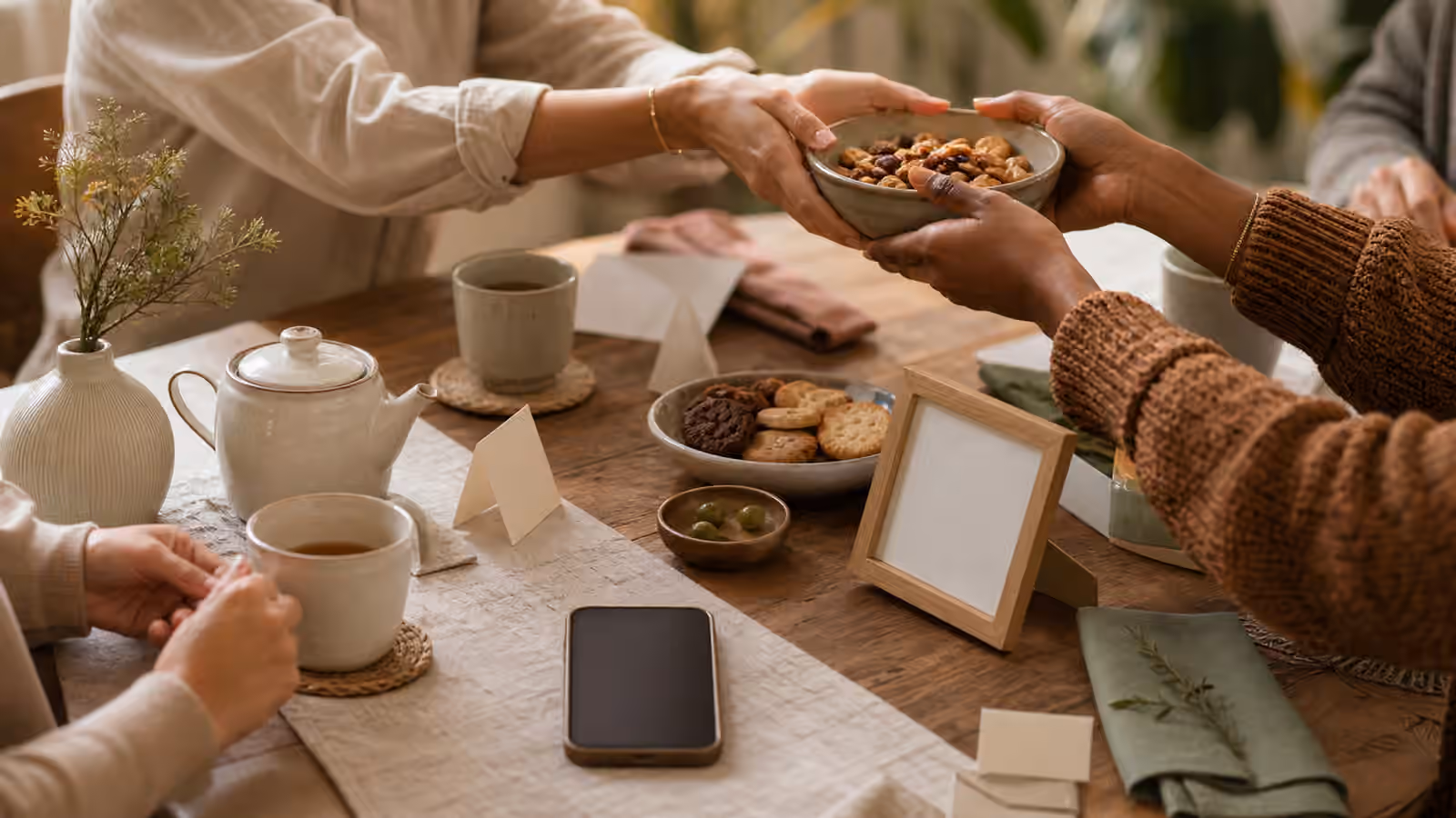 a small table with tea, snacks, blank cards, a face-down phone, and an empty photo frame