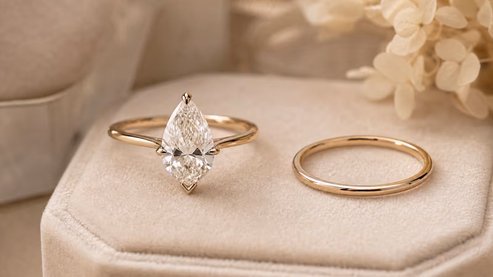 Pear-shaped diamond engagement ring with a protective V-prong on a velvet ring pad.