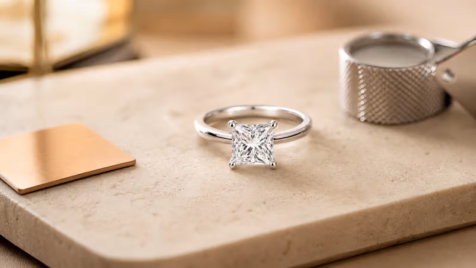Princess-cut diamond engagement ring with protected corners on a stone jewelry tray.