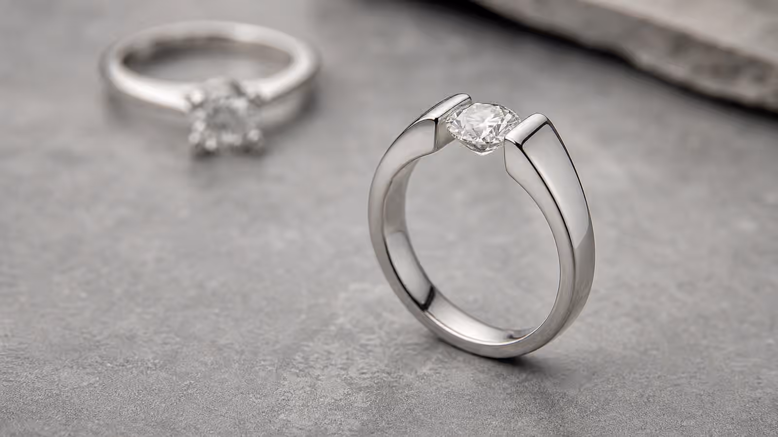 Modern tension-style engagement ring with the center diamond held between two metal arms.