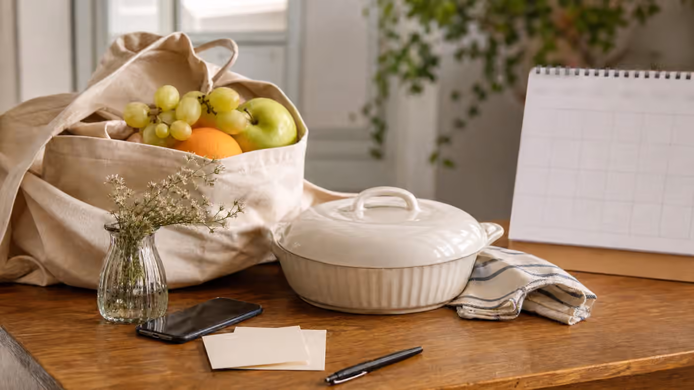 A covered dish, fruit tote, blank note cards, and a face-down phone arranged for quiet community care.