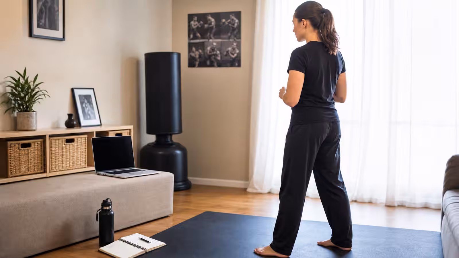 A Krav Maga student reviewing a blank-screen training video setup in a cleared home practice space.