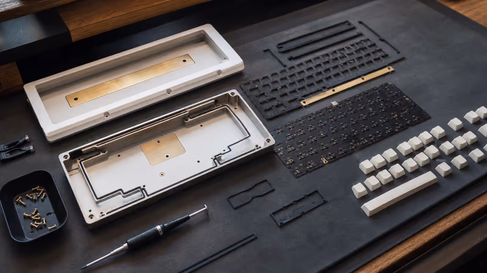 Opened custom keyboard case with PCB, plate, gaskets, and screws arranged for assembly.