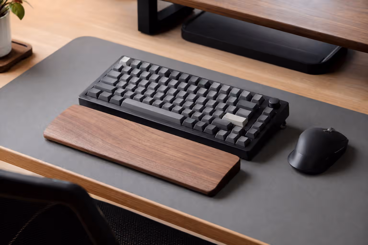 Compact mechanical keyboard on a desk mat with a wrist rest and mouse placed close by.