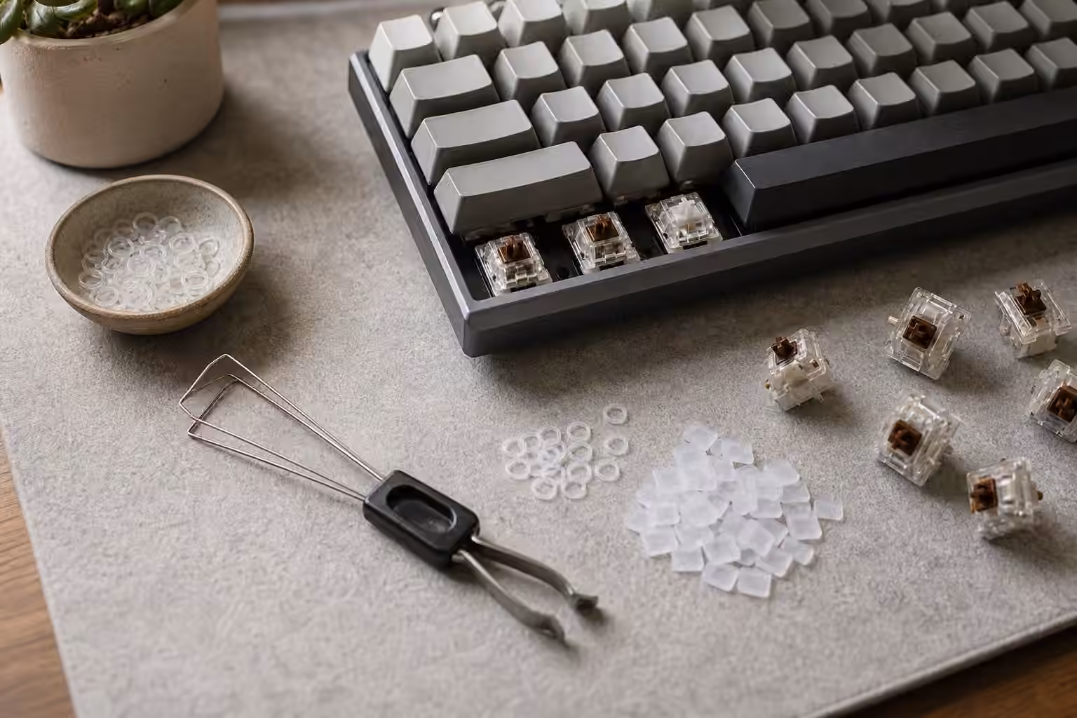 Mechanical keyboard with removed keycaps, O-rings, switch pads, puller, and loose switches on a desk mat.