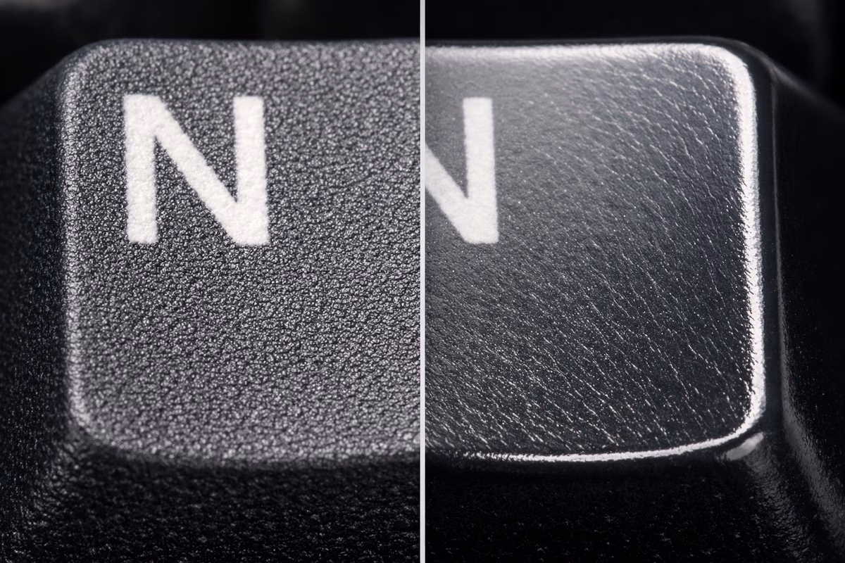 Macro split comparison shot: Left side showing the textured matte finish of a PBT keycap, Right side showing the smooth shiny surface of a worn ABS keycap, distinct texture difference visible under studio light