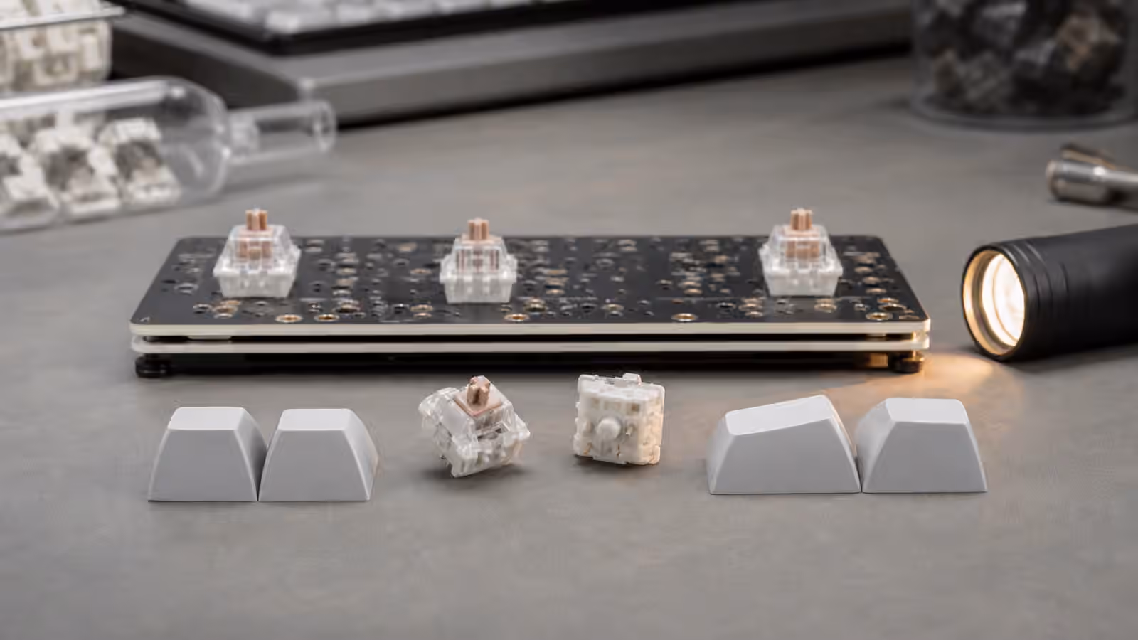 Keyboard PCB with switches and blank sculpted keycaps arranged for a side-view clearance comparison.