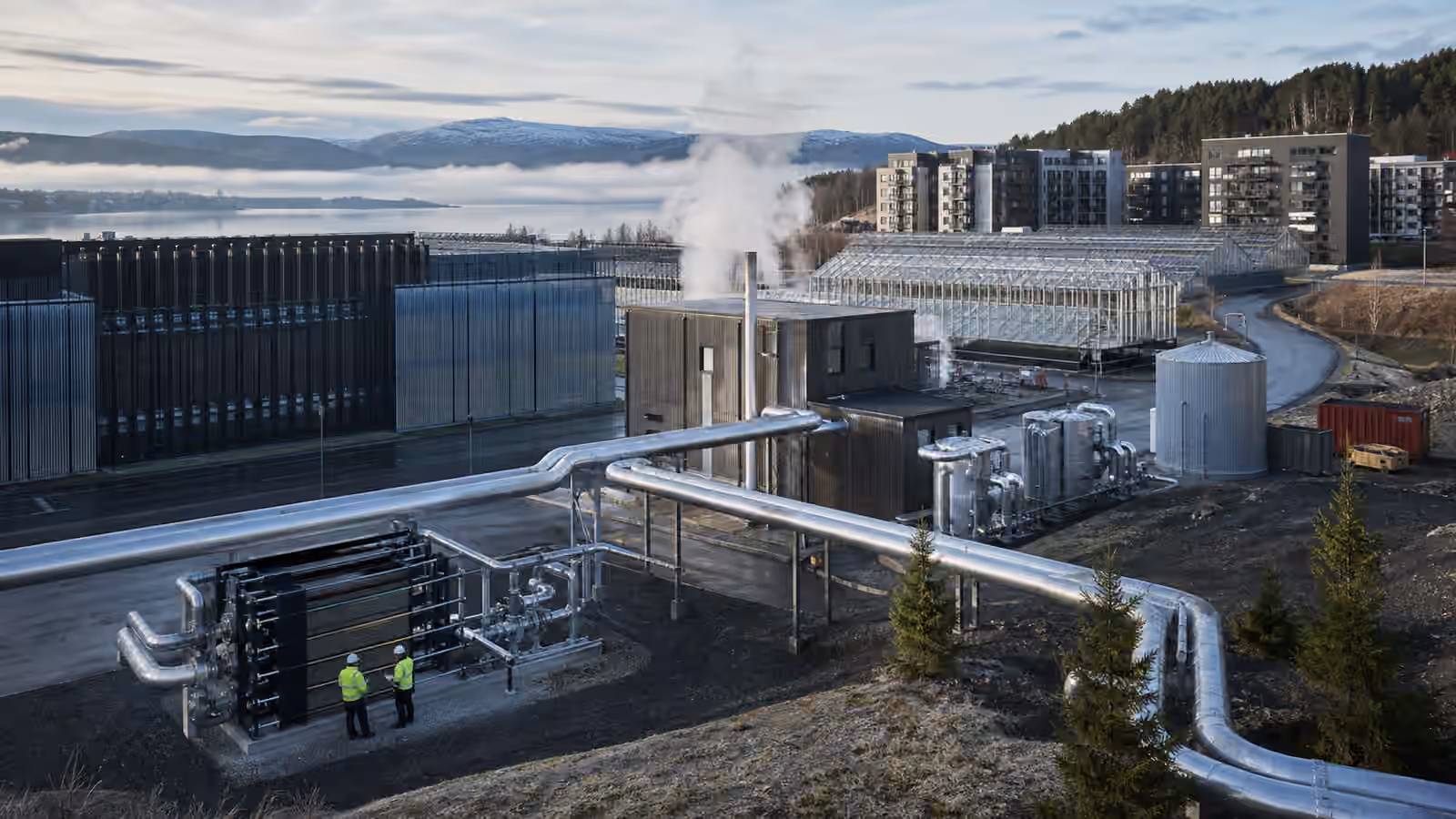 A data center and district energy plant connected by insulated heat pipes to greenhouses and apartment buildings in cool weather.